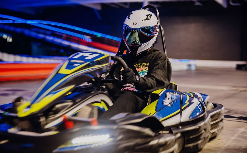 A helmeted driver racing a SODI RSX2 kart at Nitro City Racing Fairfield