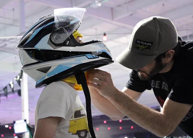 A Nitro City Racing team member fitting a helmet before indoor karting