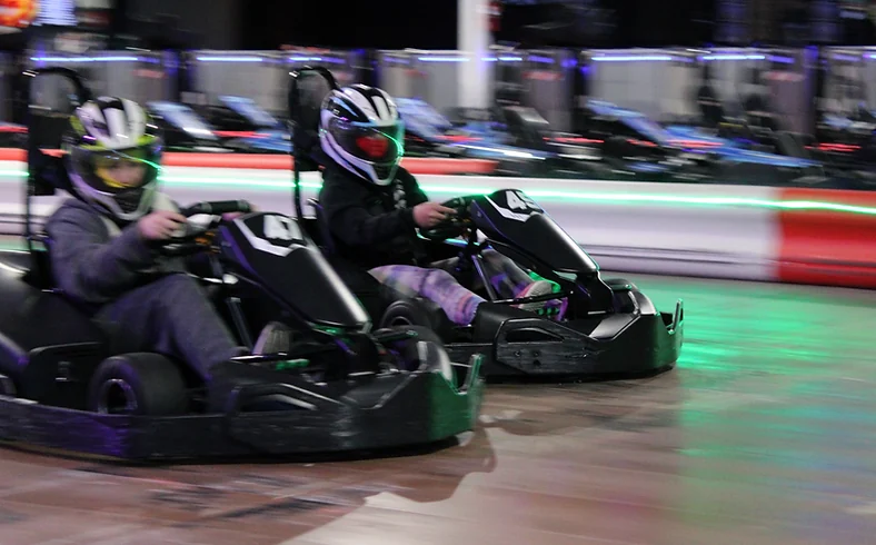 Two helmeted drivers racing side-by-side at Nitro City Racing Rohnert Park