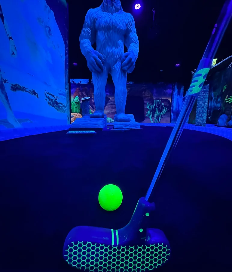 A glowing blacklight mini golf lane inside Mystic Canyon at Nitro City Racing Fairfield
