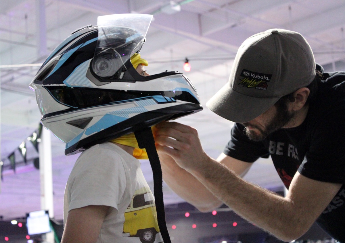A Nitro City Racing team member fitting a helmet before indoor karting