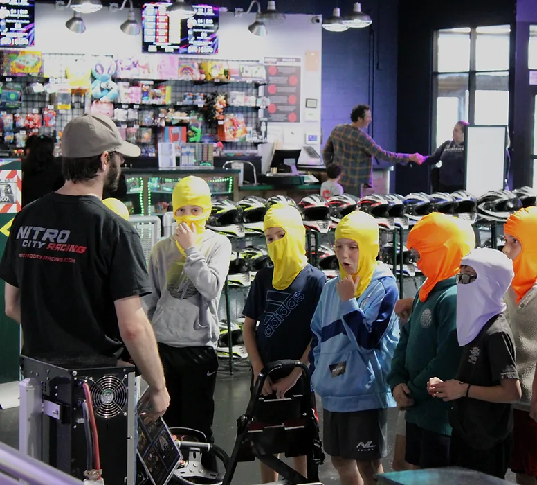 Young racers in bright headsocks listening to a karting briefing at Nitro City Racing Rohnert Park