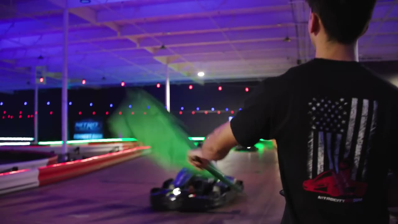 Indoor electric go-karts racing through a Nitro City Racing track corner